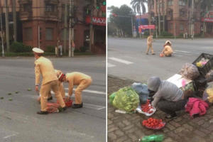 Hình ảnh đẹp của CSGT giúp tiểu thương thu gom hàng hóa rơi trên đường