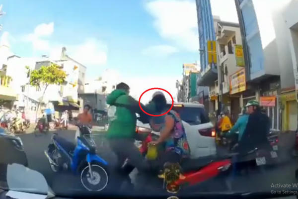 Nam thanh niên mặc trang phục Grap dùng mũ bảo hiểm phang thẳng đầu phụ nữ