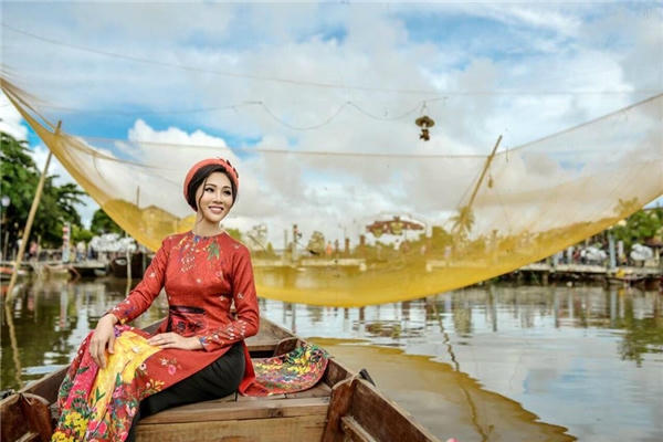 Diệu Ngọc duyên dáng giữa trời chiều Hội An với áo dài màu nâu đỏ kết hợp chiếc mấn màu đỏ cam trẻ trung.