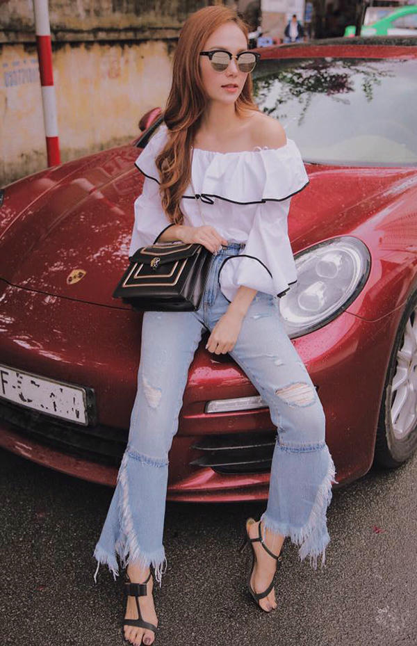 Áo trễ vai phối đường viền tương phản màu sắc được ca sĩ kết hợp cùng quần jean xé gấu và các phụ tiệp sắc đen.