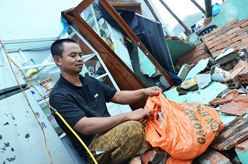 Anh Hùng nhặt kính vỡ sau trận bão bỏ vào bao tải. Ảnh: Phạm Linh.