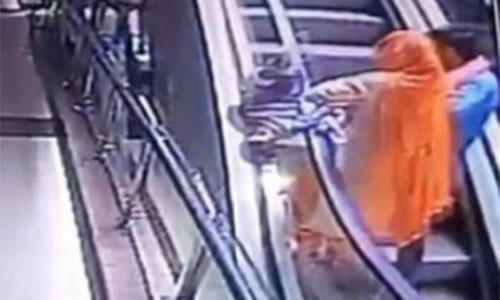 Bà mẹ để rơi con khi vừa đi thang cuốn vừa chụp ảnh. Ảnh: