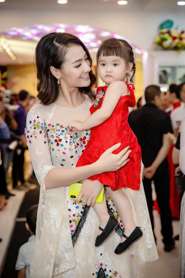 Người mẫu Hồng Quế gây chú ý khi diện áo dài đính kim sa lấp lánh và bế theo cô con gái đáng yêu. Kể từ khi con gái cứng cáp, Hồng Quế thường xuyên cho bé đi dự sự kiện cùng để chia sẻ niềm đam mê thời trang với mẹ.