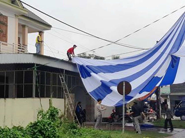  Nhiều người đội mưa để căng bạt phục vụ xem trận chung kết. 