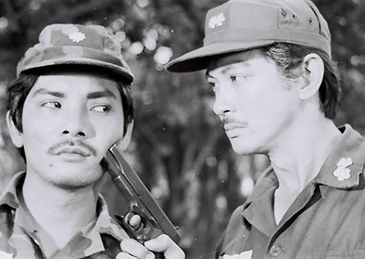Thương Tín (trái) bên Chánh Tín trong một cảnh quay của Ván bài lật ngửa. Ảnh: Hãng phim Giải Phóng./