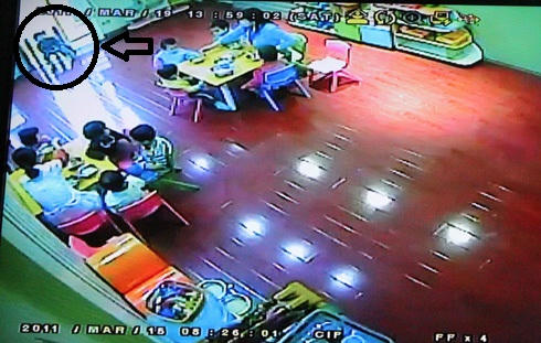 Bé Phi bị buộc vào ghế, ngồi một mình trong khi các bạn được cô cho ăn. Ảnh chụp lại từ màn hình camera ghi lại hình ảnh các cháu tại trường Little Angel hôm 15/3. Ảnh: Minh Thùy - VNExpress.