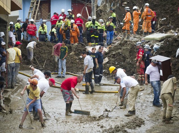 Người dân, cảnh sát và nhân viên cứu hộ đang thu dọn bùn đất tại thành phố Manizales. Ảnh AFP