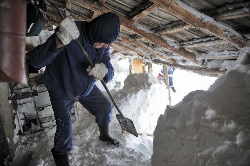 Một người đàn ông đang xúc tuyết. Ảnh: AFP