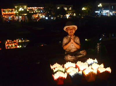 Cậu bé cứ mỗi đêm trăng rằm lại bày biện bán những chiếc đèn hoa đăng lung linh cho khách thả trôi sông.