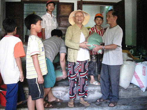 Ông NguyễnThìn (bên phải) san sẻ lộc trời bằng việc mua gạo về giúp cho những hộ nghèo đón tết