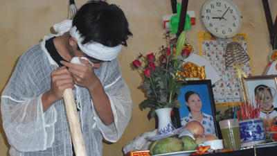 Con trai chị Vở khóc đến kiệt sức đứng chống gậy bên di ảnh của mẹ.