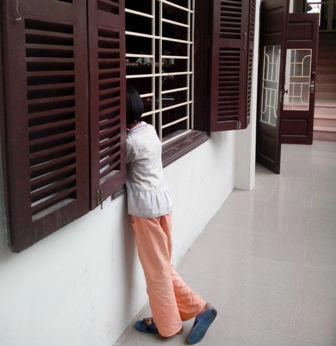 Đứa con gái thị thiểu năng lặng nhìn cảnh xử án cha qua ô cửa sổ