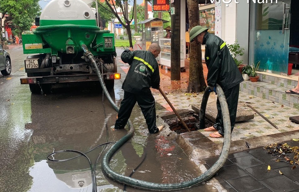 Công nhân đội mưa dọn dẹp cây hoa dập nát sau đêm khai trương phố đi bộ ở Hải Dương