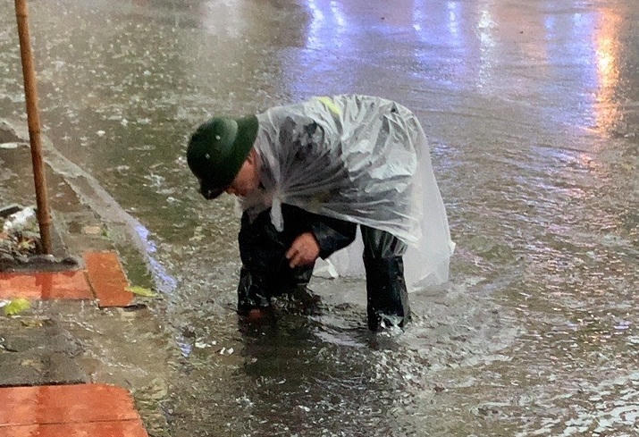 Công nhân đội mưa dọn dẹp cây hoa dập nát sau đêm khai trương phố đi bộ ở Hải Dương