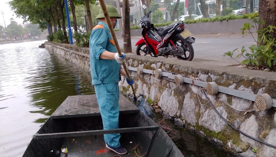 Công nhân đội mưa dọn dẹp cây hoa dập nát sau đêm khai trương phố đi bộ ở Hải Dương