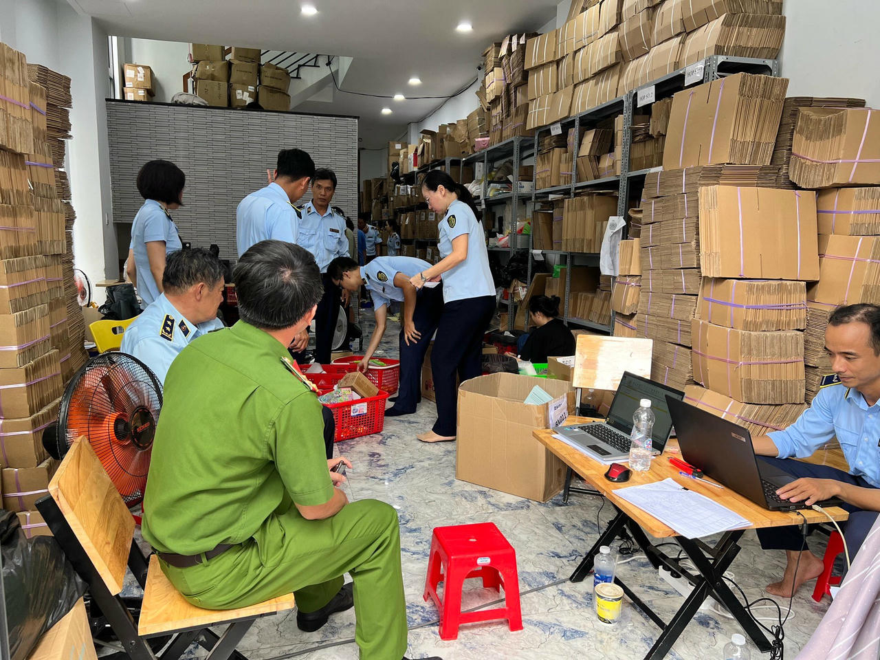  Lực lượng chức năng kiểm tra một kho hàng nghi hàng giả, không rõ nguồn gốc, xuất xứ. 
(Ảnh: QLTT TP HCM)