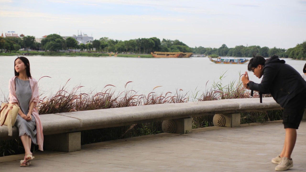 Một cặp đôi tạo dáng chụp ảnh bên bờ sông Hương, giữa những bông cỏ lau mềm mại