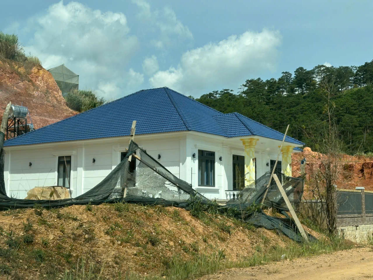Một căn nhà khang trang vừa hoàn thiện, phía sau là đồi cao.