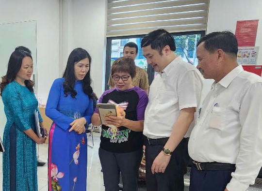 Hỗ trợ người dân thao tác thực hiện thủ tục hành chính trên thiết bị thông minh tại Điểm phục vụ hành chính công phường Cầu Giấy. (Ảnh: H.Hà)