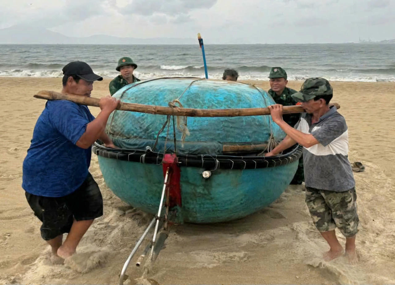Lực lượng chức năng hỗ trợ người dân đưa thuyền thúng lên bờ trú bão.