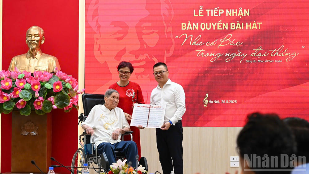 Tổng Biên tập Lê Quốc Minh nhận bản thảo bài hát Như có Bác trong ngày đại thắng có chữ ký đề tặng của nhạc sĩ Phạm Tuyên. (Ảnh: THÀNH ĐẠT)