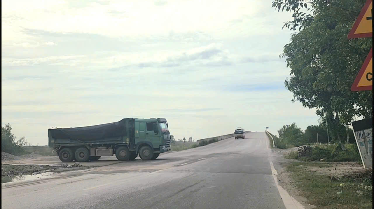 Đoàn xe tải từ trong đường công vụ dưới chân cầu vượt lao lên rẽ vào cầu trên tuyến Quốc lộ 48 khiến nhiều xe phải dừng nhường đường.