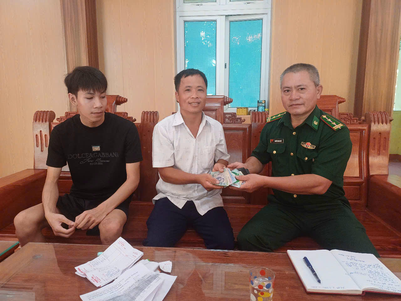 Cán bộ Đồn Biên phòng Nhật Lệ cùng đại diện 4 em học sinh trao trả tài sản cho người bị mất.