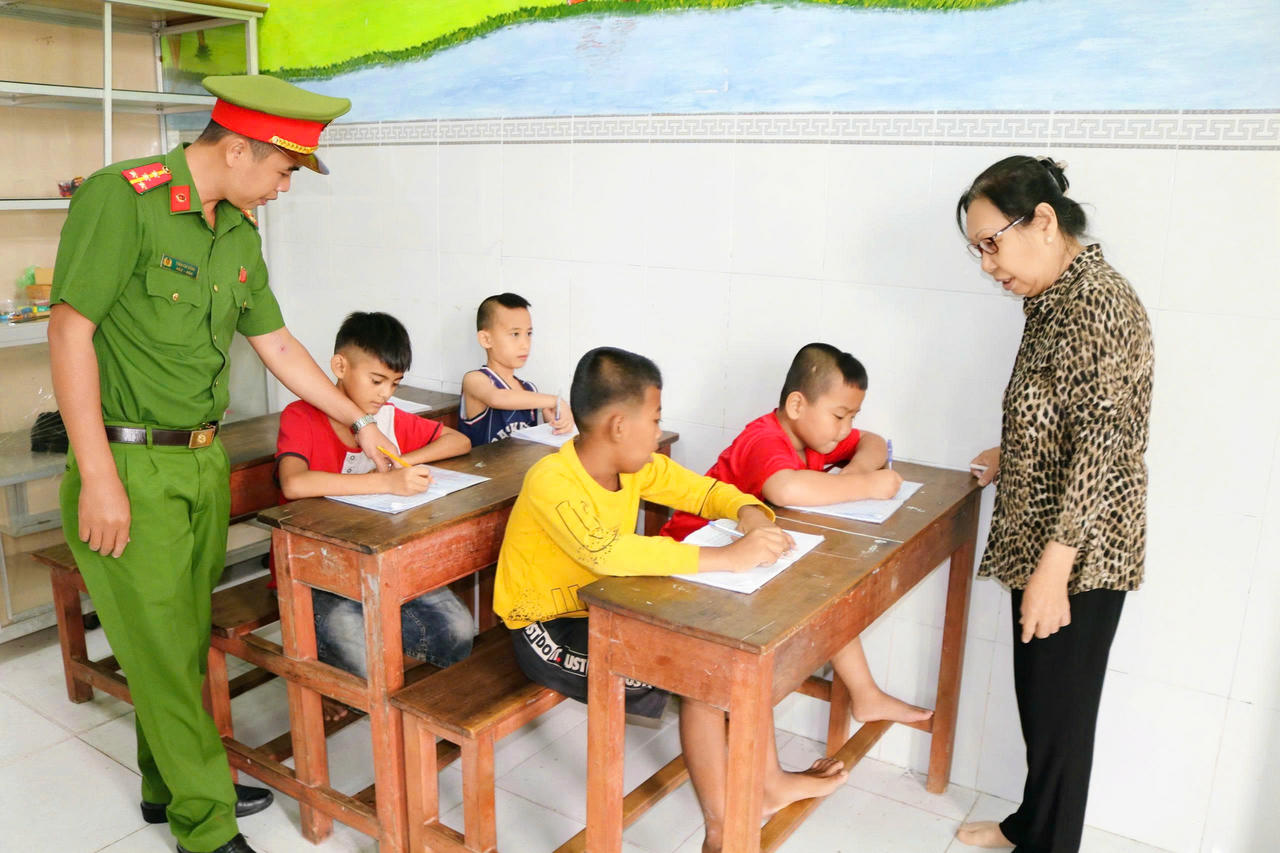 Cán bộ Công an phường Vĩnh Trạch hỗ trợ 5 em nhỏ theo học tại lớp học tình thương. (Ảnh trong bài: PV)