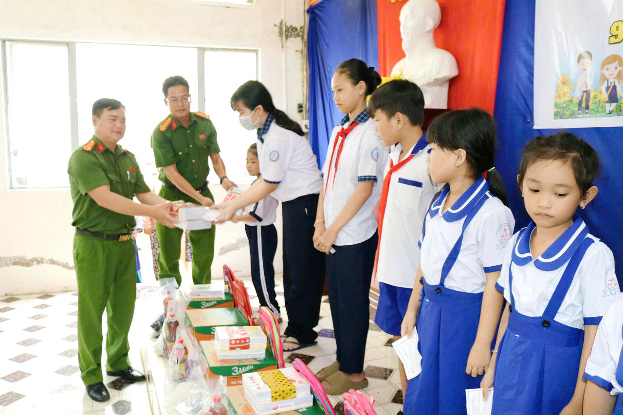 Cán bộ Công an phường Vĩnh Trạch trao tặng quà, cặp và sách cho học sinh có hoàn cảnh khó khăn trên địa bàn.