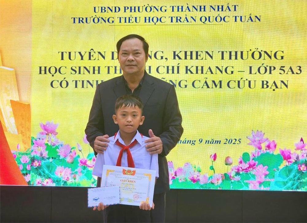 Ông Trần Xuân Kỳ - Hiệu trưởng nhà trường khen thưởng em Thạch Chí Khang. (Ảnh TT)