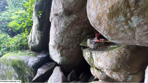 “Một khối đá trong rừng sâu núi Cấm – nơi được người dân tin là tọa độ đặt cây thẻ số 5 Trung Ương Huỳnh Đế. Dù dấu khắc đã không còn rõ, niềm tin và sự tôn kính với di tích này vẫn hiện diện qua từng nén nhang và lời khấn.”. Cổng vào Hang Ông Thẻ – nơi lưu giữ cây thẻ số 5 bí ẩn.