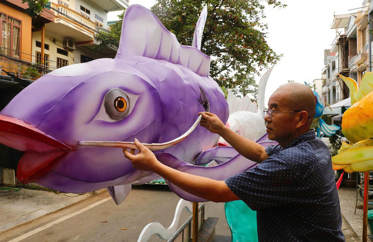 Ông Phạm Ngọc Toán và mô hình đàn cá chép khổng lồ.(Ảnh: Huy An)