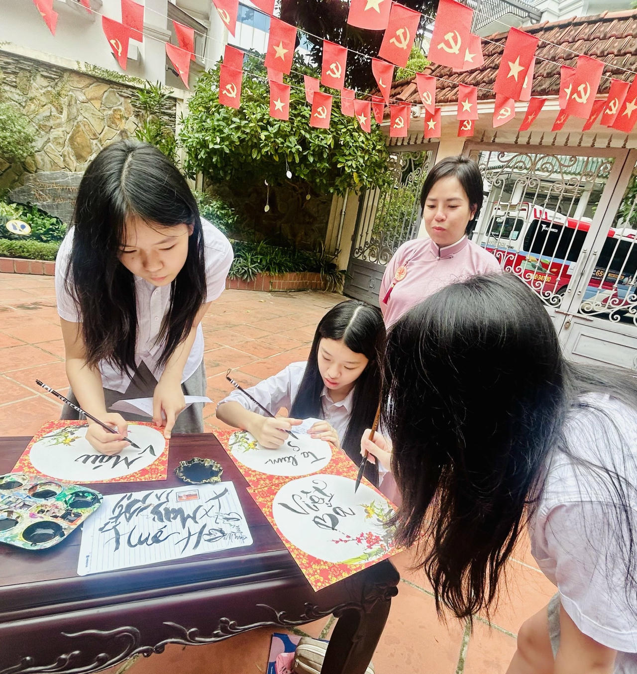 Chị Nguyễn Thị Thu Trang hướng dẫn học sinh viết thư pháp theo những câu thơ của nhà thơ Tố Hữu (Ảnh: Thùy Dương).