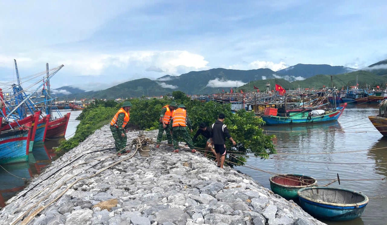 Cán bộ, chiến sĩ Đồn Biên phòng Roòn giúp ngư dân
neo đậu tàu thuyền.