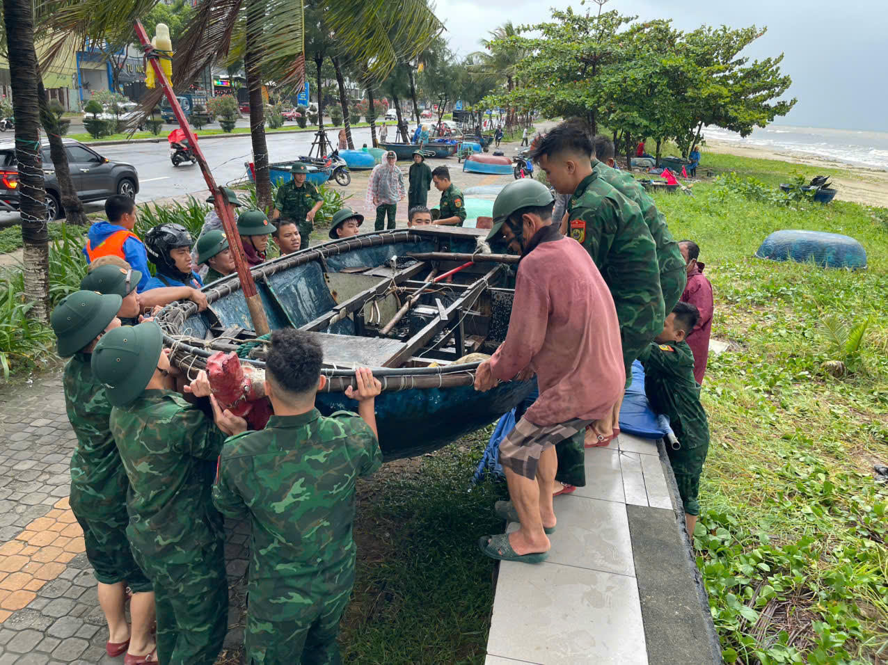 Lực lượng chức năng hỗ trợ ngư dân đưa thuyền thúng từ vịnh Đà Nẵng lên bờ tránh bão.