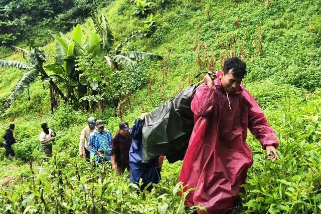 Lực lượng chức năng khiêng vong băng qua 5km đường rừng hiểm trở đưa bệnh nhân người Lào về nhà. Ảnh: N.T