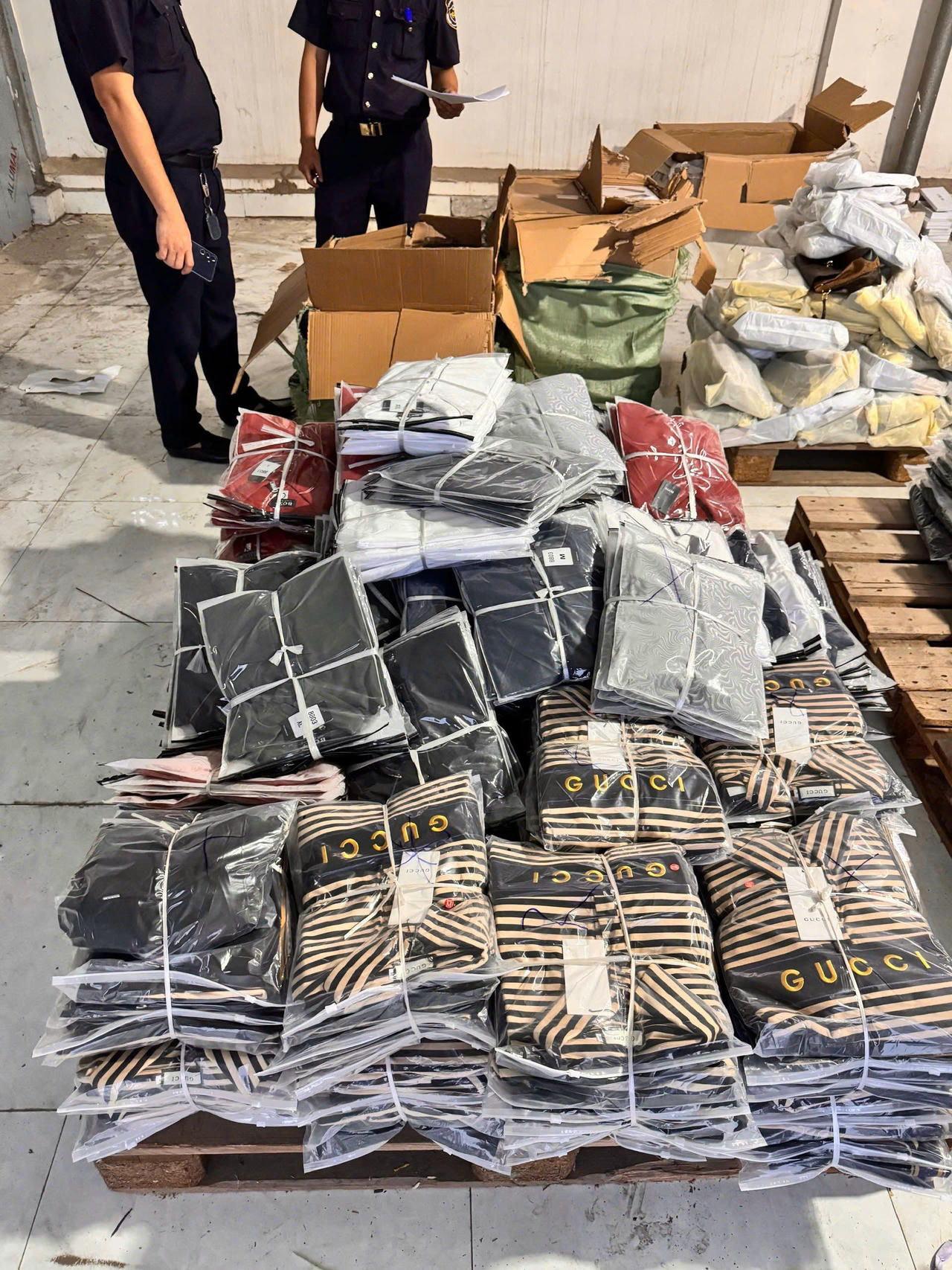 Lô hàng điện thoại di động nghi giả nhãn hiệu đã dùng quần áo để ngụy trang. (Ảnh: N.Linh)