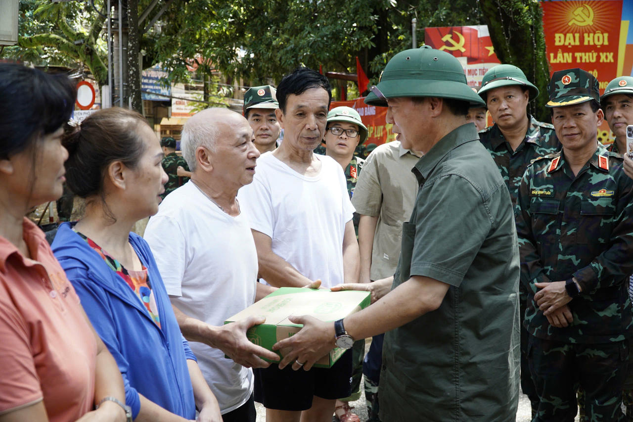 Phó Thủ tướng Chính phủ Trần Hồng Hà tặng quà, động viên các hộ dân phường Phục Phán bị ngập nhà hoàn toàn. (Ảnh: Tiến Dũng)