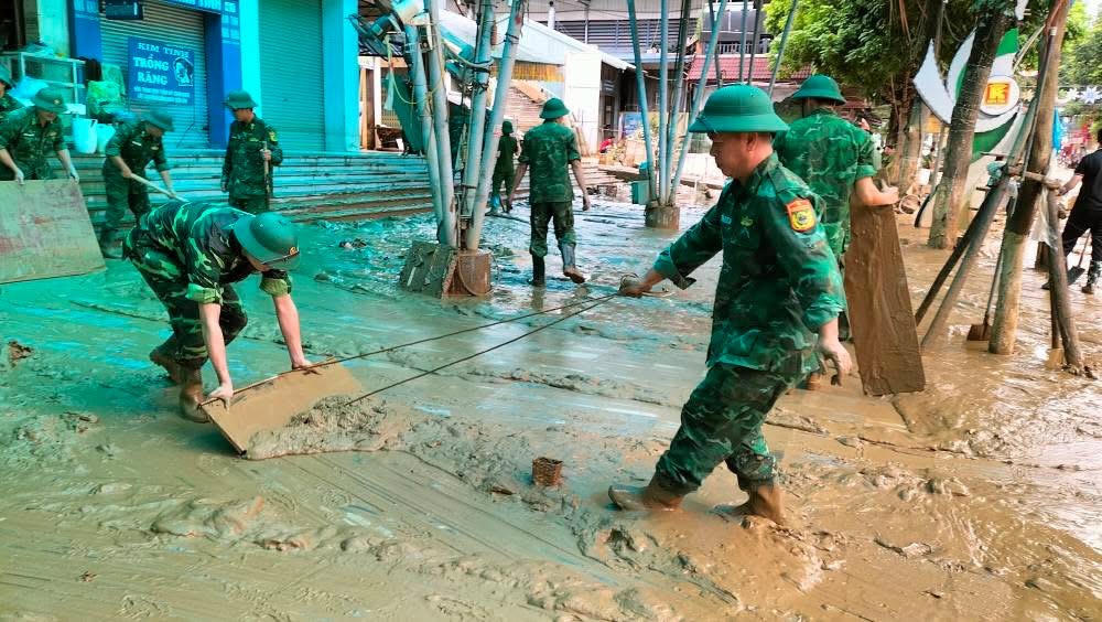Cơ quan chức năng, bộ đội hỗ trợ người dân khắc phục hậu quả sau khi nước rút. (Ảnh: PV)