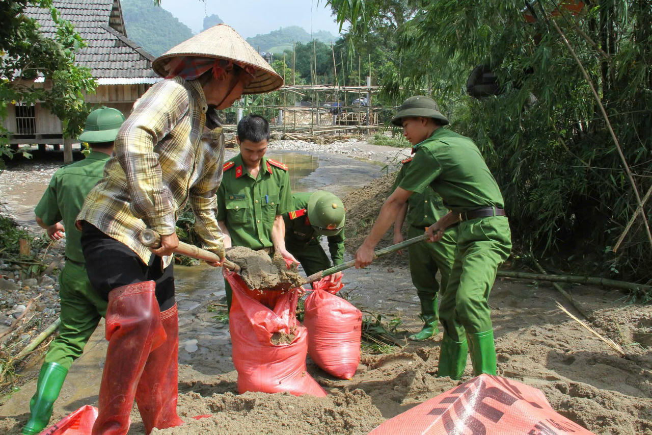 Công an xã hỗ trợ nhân dân làm bao cát chống lũ.