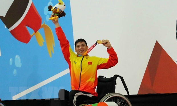 Vận động viên Võ Thanh Tùng tự hào giơ cao
tấm huy chương vàng thứ 3 tại Asian Para Games 2018.
(Nguồn: TTXVN)