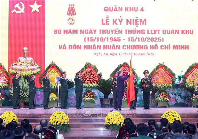 Tổng Bí thư Tô Lâm gắn Huân chương Hồ Chí Minh lên lá cờ truyền thống của Quân khu 4. Ảnh: Thống Nhất/TTXVN