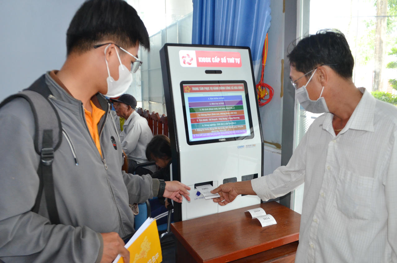 Người dân lấy số thứ tự tại kiosk điện tử ở Trung tâm Phục vụ hành chính công xã Hòa Bình.