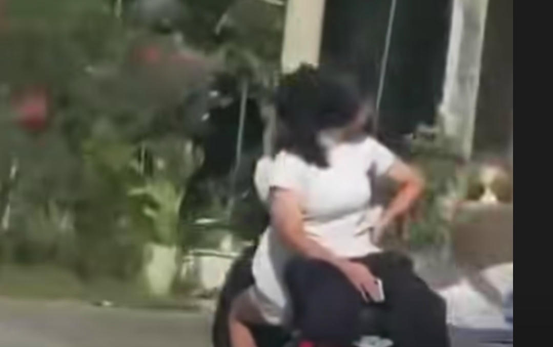 Một đoạn video ghi lại cảnh nữ sinh ngồi sau quay mặt ra phía sau và dựa lưng vào lái xe. Ảnh cắt từ clip.