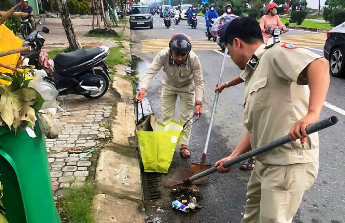 Lực lượng quản lý đô thị dọn dẹp vệ sinh, khơi thông cống rãnh trên đường Nguyễn Tất Thành.
