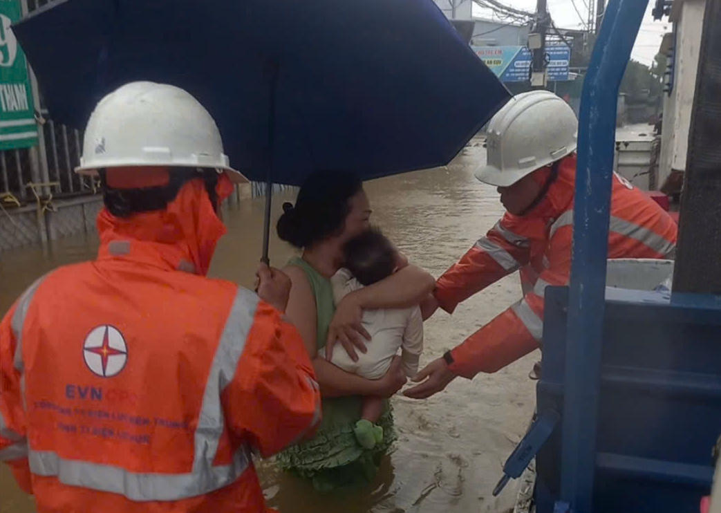Nhân viên EVN giúp mẹ ôm trẻ nhỏ chạy lũ.