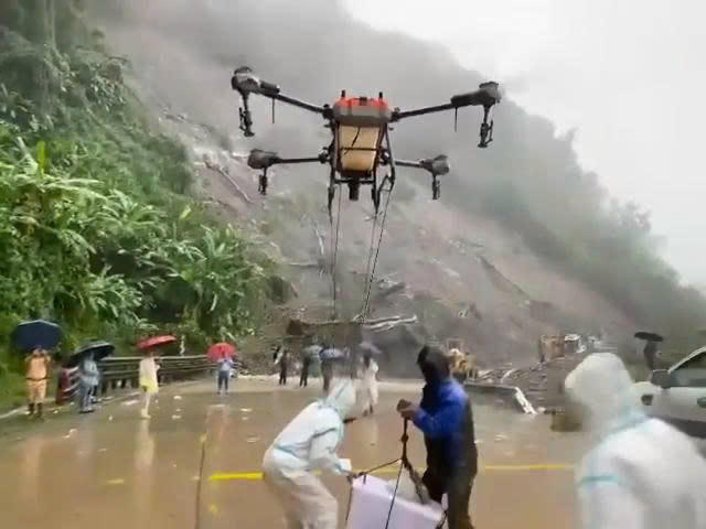 Lực lượng chức năng cùng người dân sử dụng drone tiếp tế nhu yếu phẩm cho tài xế mắc kẹt trên đèo Lò Xo. (Ảnh: Cắt từ clip)
