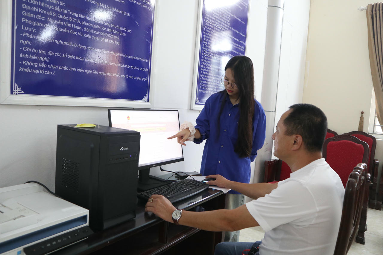 Đoàn thanh niên đang hỗ trợ, hướng dẫn người dân tra cứu thông tin trên cổng Thông tin Quốc gia khi đến làm TTHC tại trung tâm.