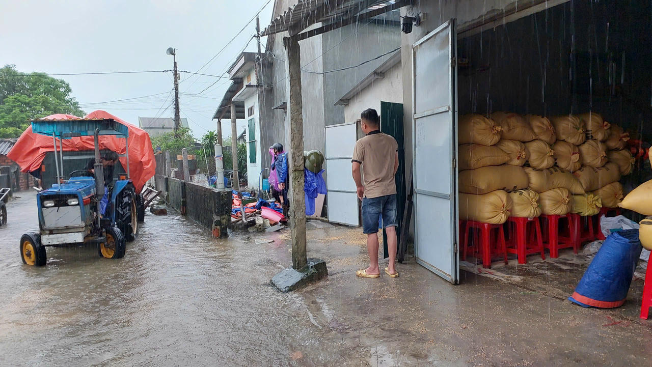 Người dân dùng máy cày vận chuyển lúa chạy lụt trong mưa lớn.