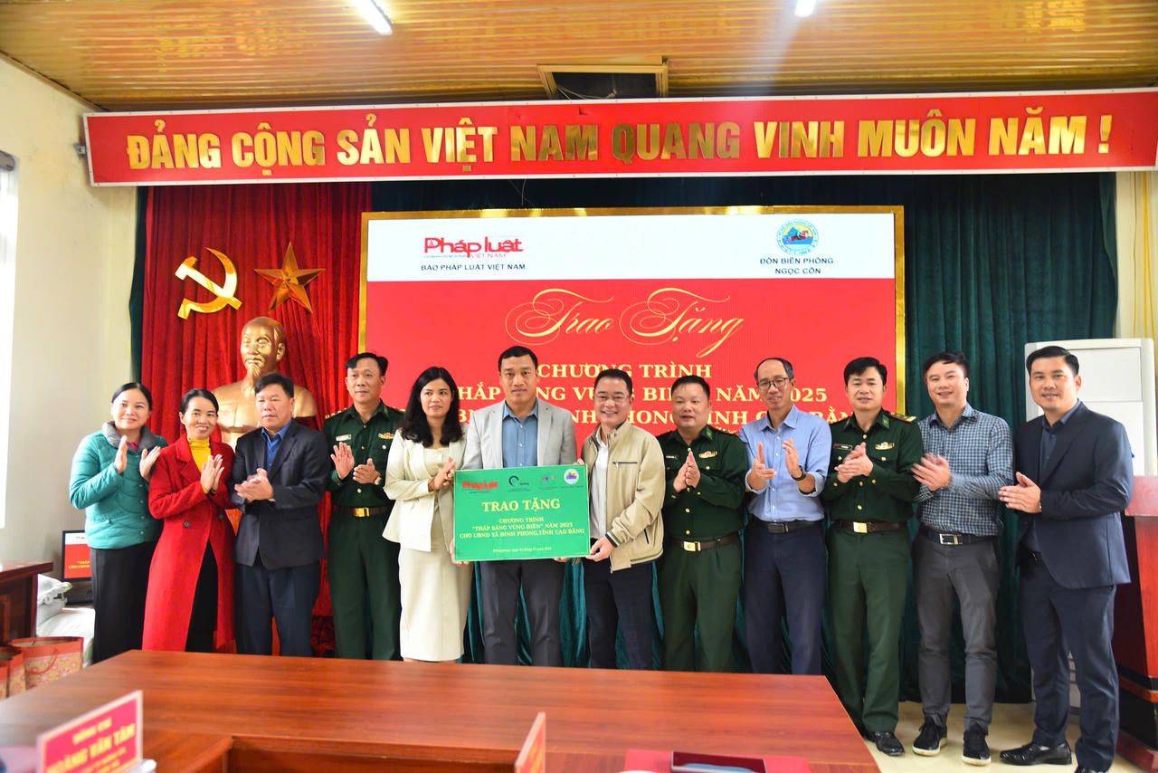 Tiến sĩ Vũ Hoài Nam, Tổng Biên tập Báo Luật Việt Nam trao tặng công trình "Thắp sáng vùng biên" cho UBND xã Đình Phòng. (Ảnh: Thanh Tùng)